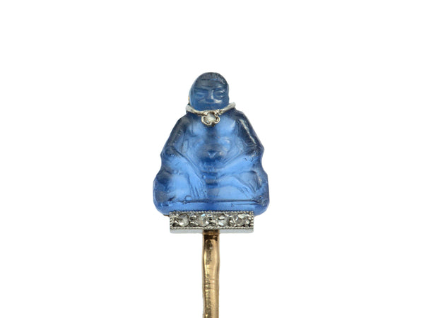 Detail of French stick pin with blue glass Buddha decorated with diamonds in platinum and yellow gold, shown on white background.