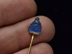 thumbnail of Detail of French stick pin with blue glass Buddha decorated with diamonds in platinum and yellow gold, shown on hand.