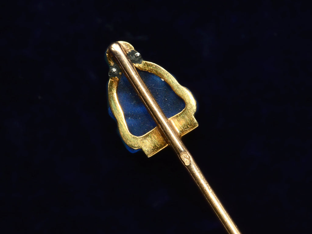 Reverse side detail of French stick pin with blue glass Buddha decorated with diamonds in platinum and yellow gold, shown on dark background.