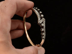 thumbnail of Hand holding an antique French silver topped yellow gold bracelet with a zig-zag of rose cut diamonds, shown on black background.