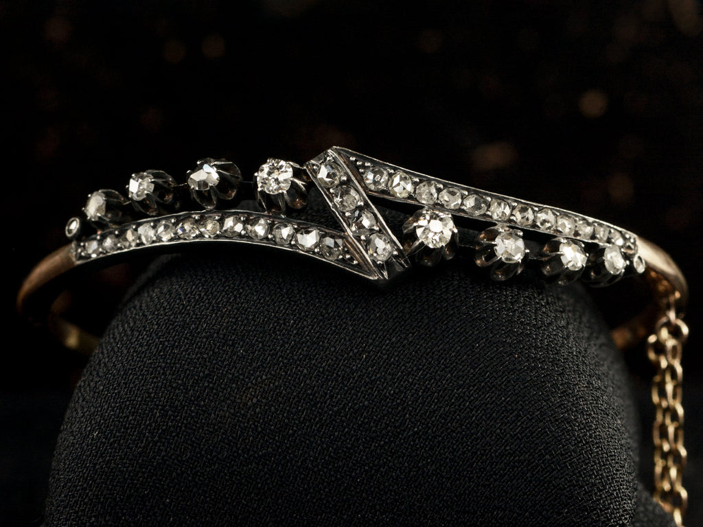 An antique French silver topped yellow gold bracelet with a zig-zag of rose cut diamonds, shown on black background.