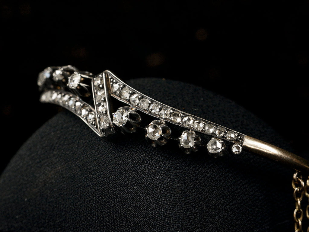 Angled view o an antique French silver topped yellow gold bracelet with a zig-zag of rose cut diamonds, shown on black background.