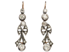 thumbnail of A pair of c1890 Victorian drop earrings with old European cut diamonds set in silver topped gold with a bow design. Shown on white background.