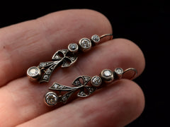 thumbnail of A pair of c1890 Victorian drop earrings with old European cut diamonds set in silver topped gold with a bow design. Shown on hand