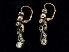 thumbnail of Side view of a pair of c1890 Victorian drop earrings with old European cut diamonds set in silver topped gold with a bow design. Shown on black background.