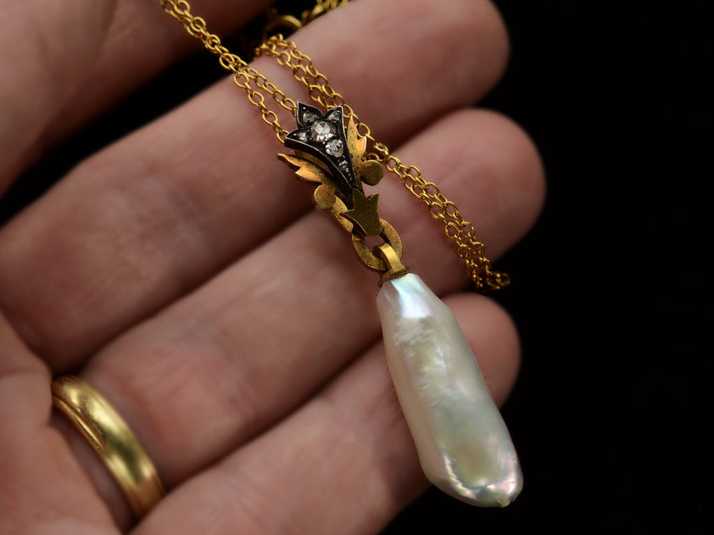 Detail of antique pendant with rose cut diamond and yellow gold top and large baroque pearl drop (shown on hand)