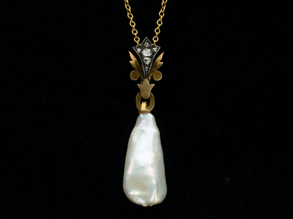 Detail of antique pendant with rose cut diamond and yellow gold top and large baroque pearl drop (shown on black background)