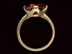 thumbnail of Side profile view of shield shaped orangey red stone set in 18K yellow gold, on dark background.