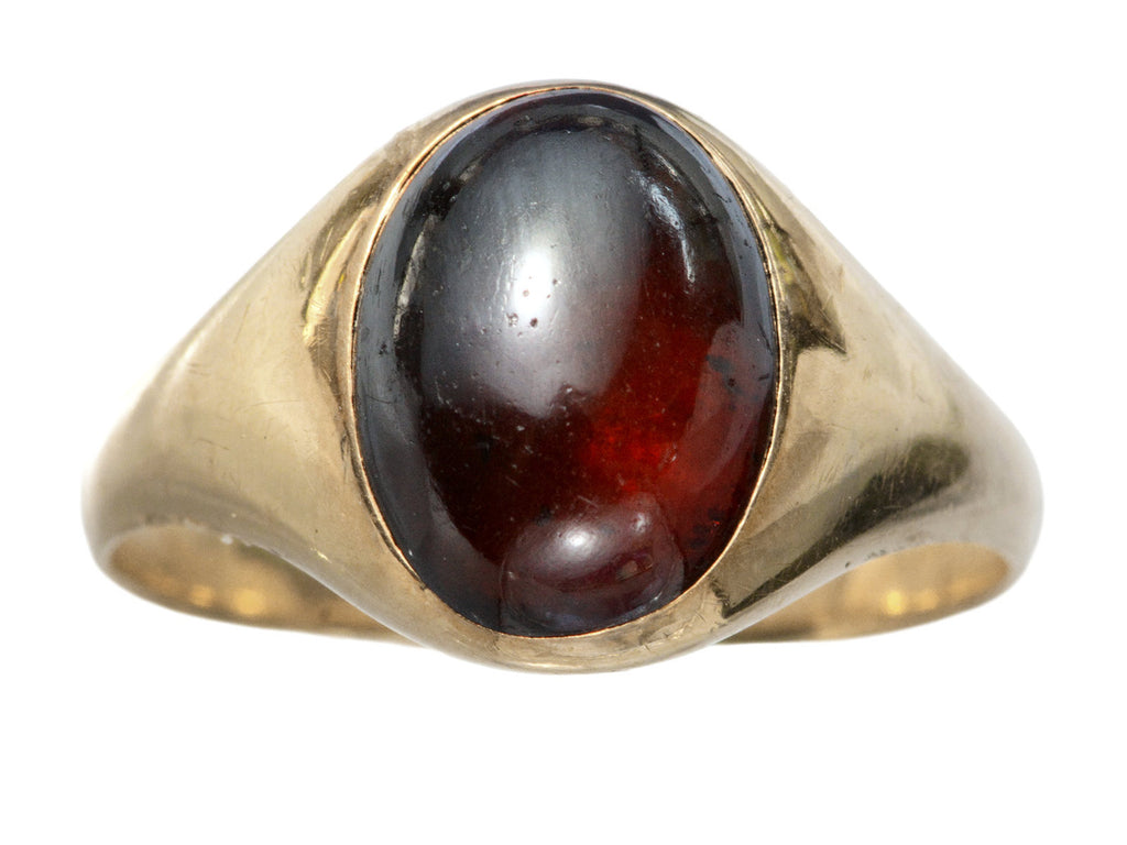 A domed antique yellow gold ring with a flush set oval dark red garnet cabochon. Shown on white background.