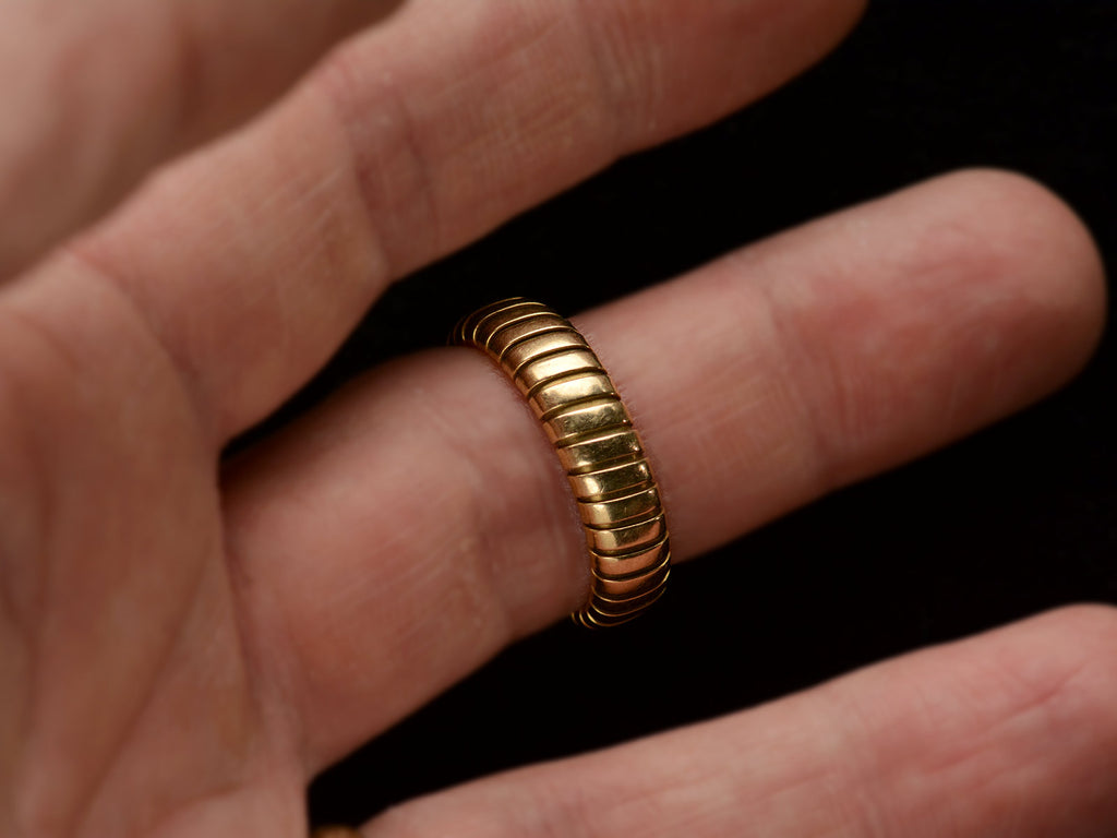 A flexible gaspipe-link 18k yellow gold band, shown on finger.