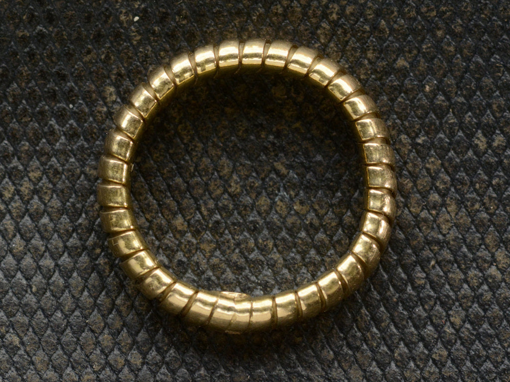 Side profile of a flexible gaspipe-link 18k yellow gold band, shown on dark background.