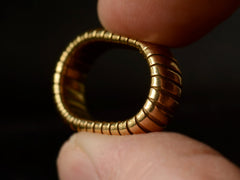 thumbnail of A flexible gaspipe-link 18k yellow gold band, shown flexed between two fingers.
