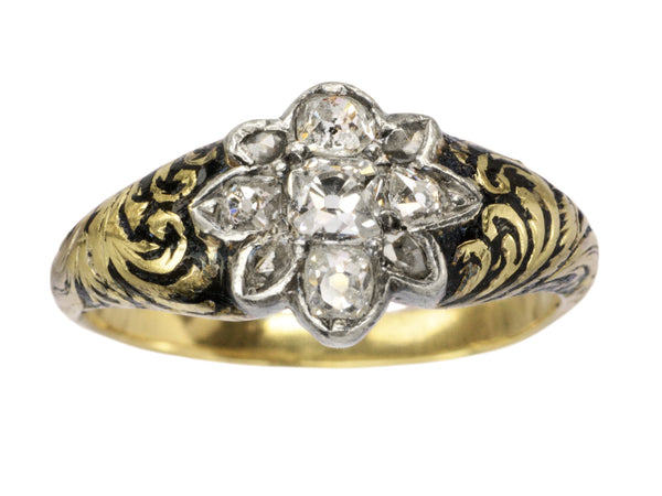 Antique c1840 diamond cluster ring in silver topped yellow gold with black enamel scroll designs on the shoulders, shown on white background.