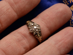 thumbnail of Antique c1840 diamond cluster ring in silver topped yellow gold with black enamel scroll designs on the shoulders, shown on finger.