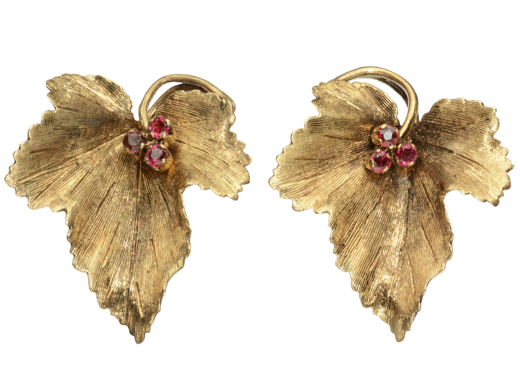 Pair of grape leaf shaped earrings in 18K yellow gold with ruby centers, shown on white background.