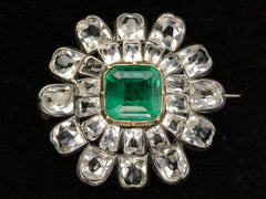 thumbnail of Face on view of 19th century silver and gold brooch with a green crystal surrounded by petals of clear white faceted crystals, shown on dark background.