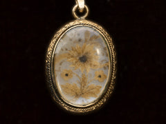 thumbnail of Victorian gold mourning pendant with blond hair arrange in a floral design on iridescent mother of pearl, shown on black background.