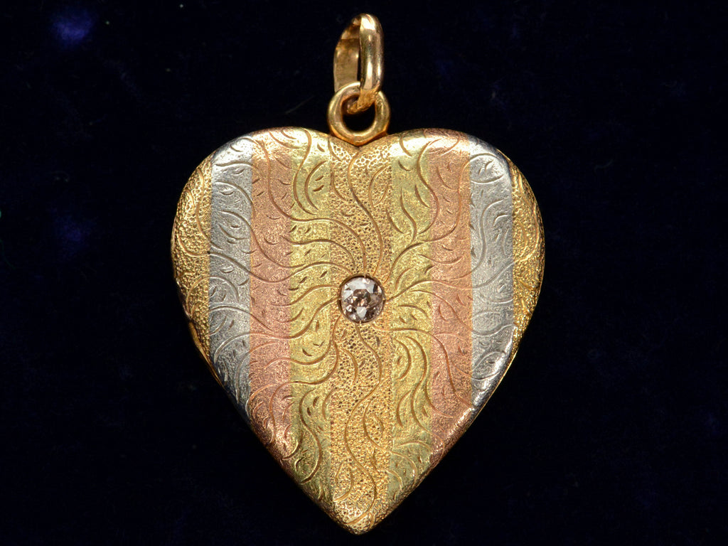 c1900 Heart Locket in yellow gold with stripes of platinum and rose gold and a pink diamond center, shown on black background