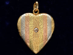 thumbnail of c1900 Heart Locket in yellow gold with stripes of platinum and rose gold and a pink diamond center, shown on black background