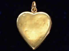 thumbnail of Reverse side of c1900 Heart Locket in yellow gold with stripes of platinum and rose gold and a pink diamond center, showing small dents.