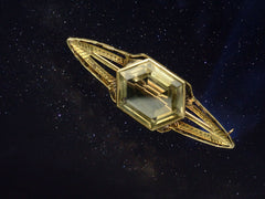 thumbnail of Antique Art Deco brooch with hexagonal citrine and gold wings, resembling a flying saucer, shown superimposed on starry night sky.