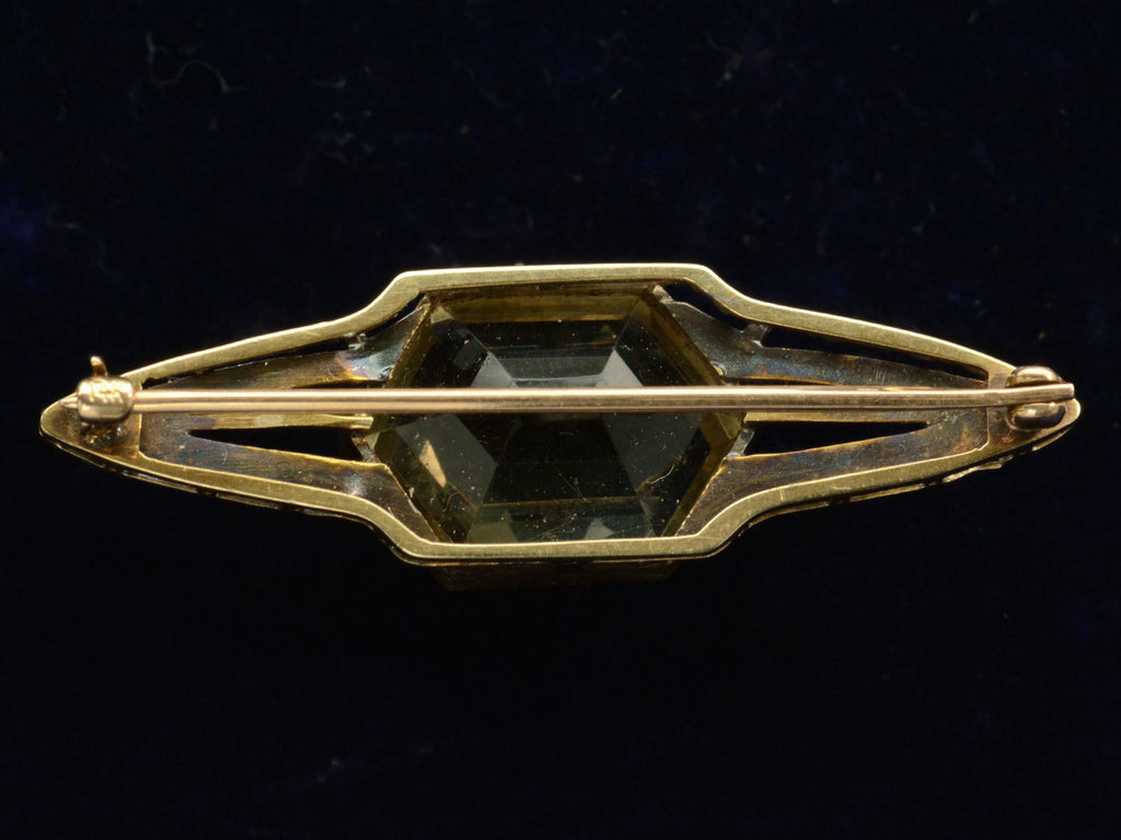Reverse side of antique Art Deco brooch with hexagonal citrine and gold wings, shown on dark background.