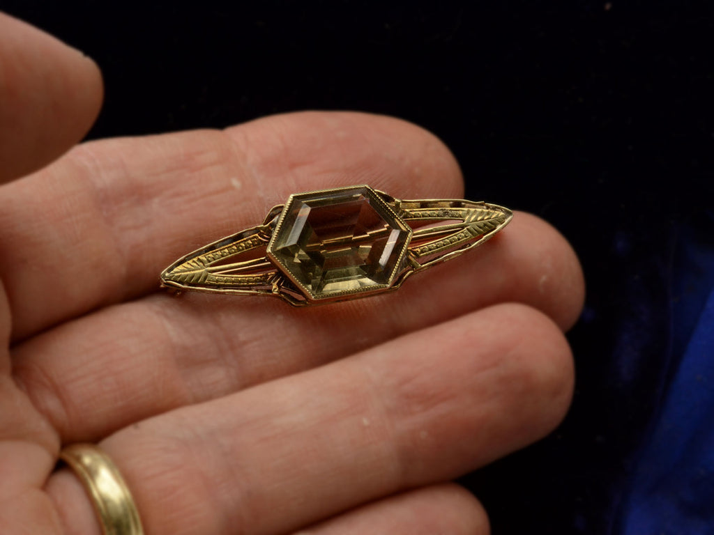 Antique Art Deco brooch with hexagonal citrine and gold wings, shown on hand