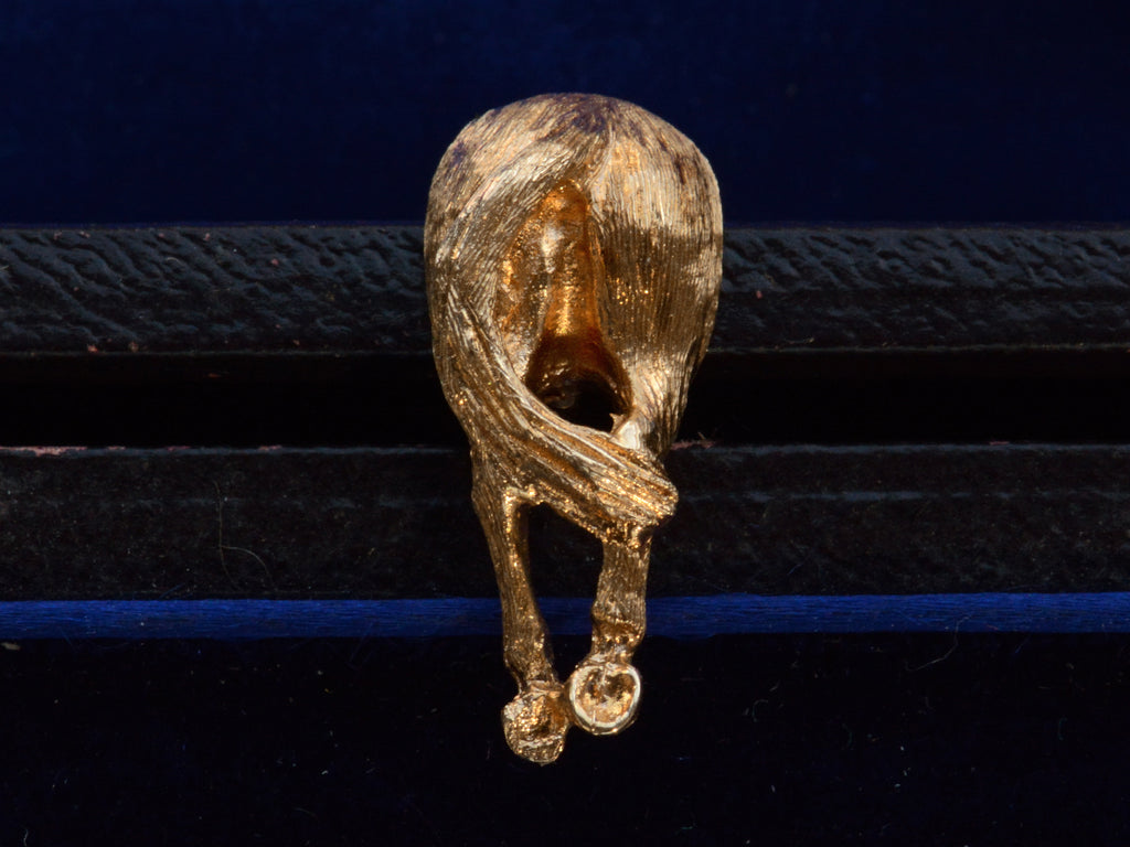 Vintage yellow gold tie tack in the form of a horse's ass. Shown on dark blue background.