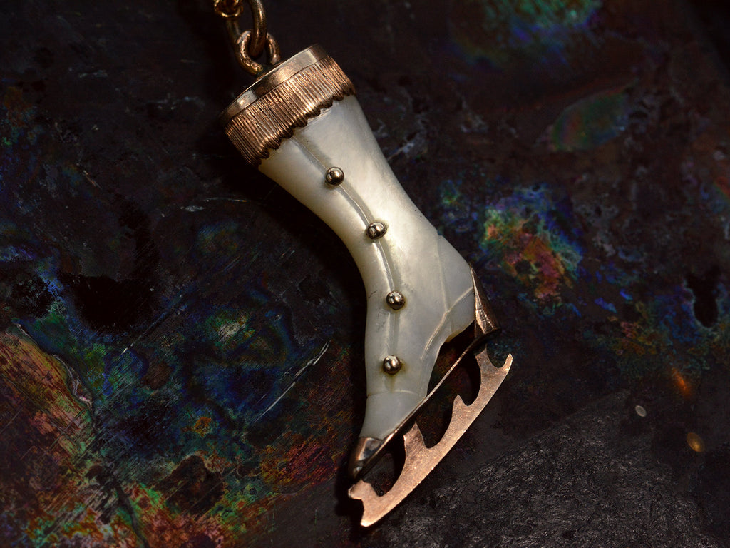 Front of antique ice skate pendant with mother of pearl and rosy gold fittings (on dark colorful background)