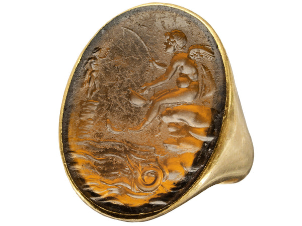 Antique yellow gold signet ring with amber glass intaglio of classical scene (Eros fishing), shown on white background.