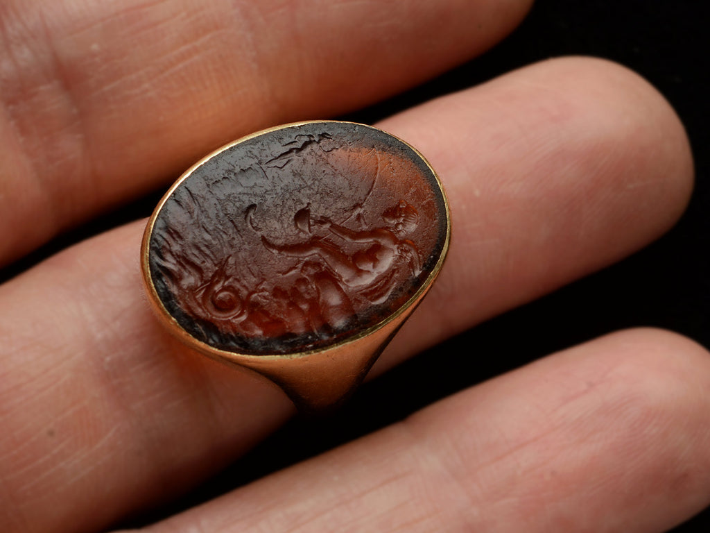 Antique yellow gold signet ring with amber glass intaglio of classical scene (Eros fishing), shown on finger