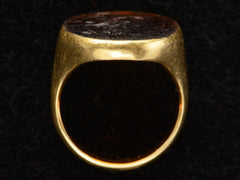 thumbnail of Side profile of antique yellow gold signet ring with amber glass intaglio of classical scene (Eros fishing), shown on dark background.