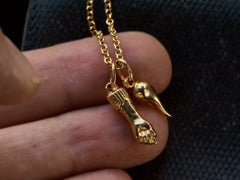 thumbnail of A pair of vintage 18K yellow gold Italian charms: a figa and a cornicello hanging on a cable chain, shown held in fingers. A "750" stamp is visible on the bale.