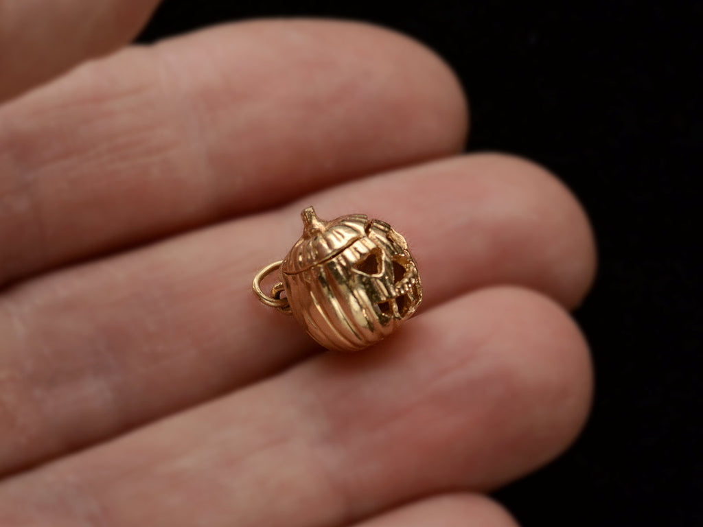 A vintage gold Jack-O'-Lantern charm, on hand.