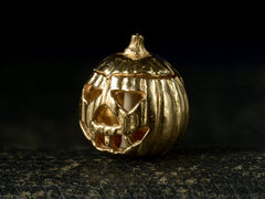 thumbnail of Angled front view of vintage gold Jack-O'-Lantern charm, on dark background.