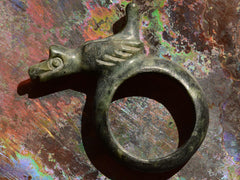 thumbnail of Angled side profile view of carved nephite jade figural ring with bird. Shown on colorful background.