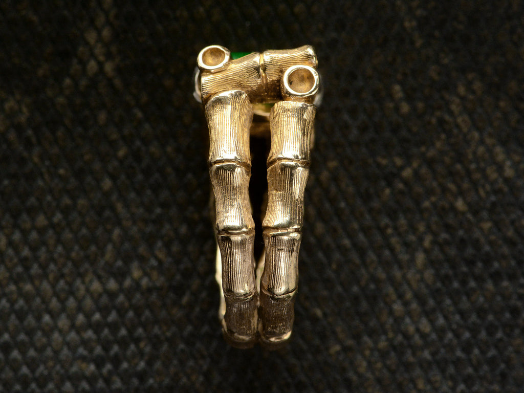 Side view of a vintage gold ring with a mounting designed to look like bamboo, shown on dark textured background.