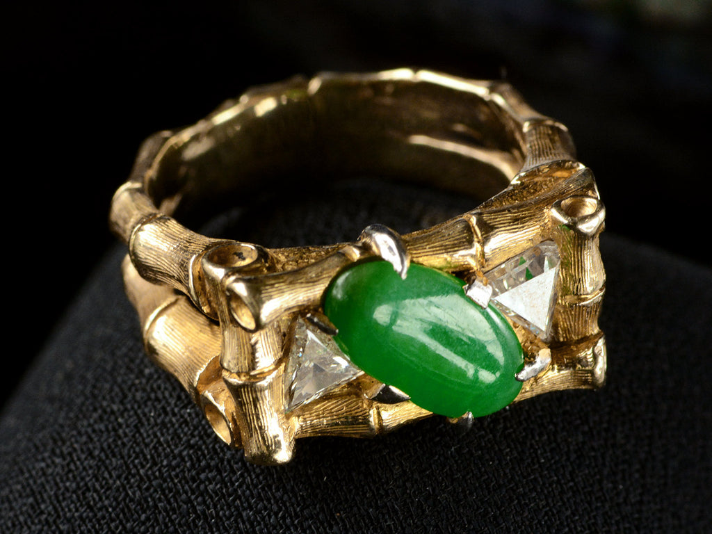 Elevated left angled view of a vintage gold jade and diamond ring with a mounting designed to look like bamboo, shown on dark background.