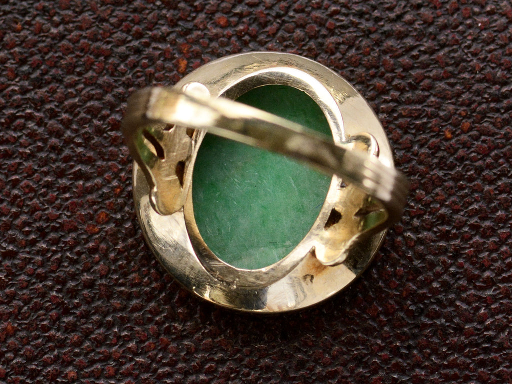 Inside view of back of antique jade and yellow gold ring, shown on textured background.