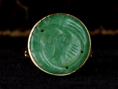 thumbnail of Front profile of c1930 yellow gold ring with a round flat jade carving mounted in a bezel, shown on dark background.