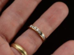 thumbnail of A vintage yellow gold and platinum wedding band with five round diamonds, shown on a finger.