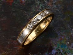 thumbnail of A vintage yellow gold and platinum wedding band with five round diamonds, shown on a dark colorful background.