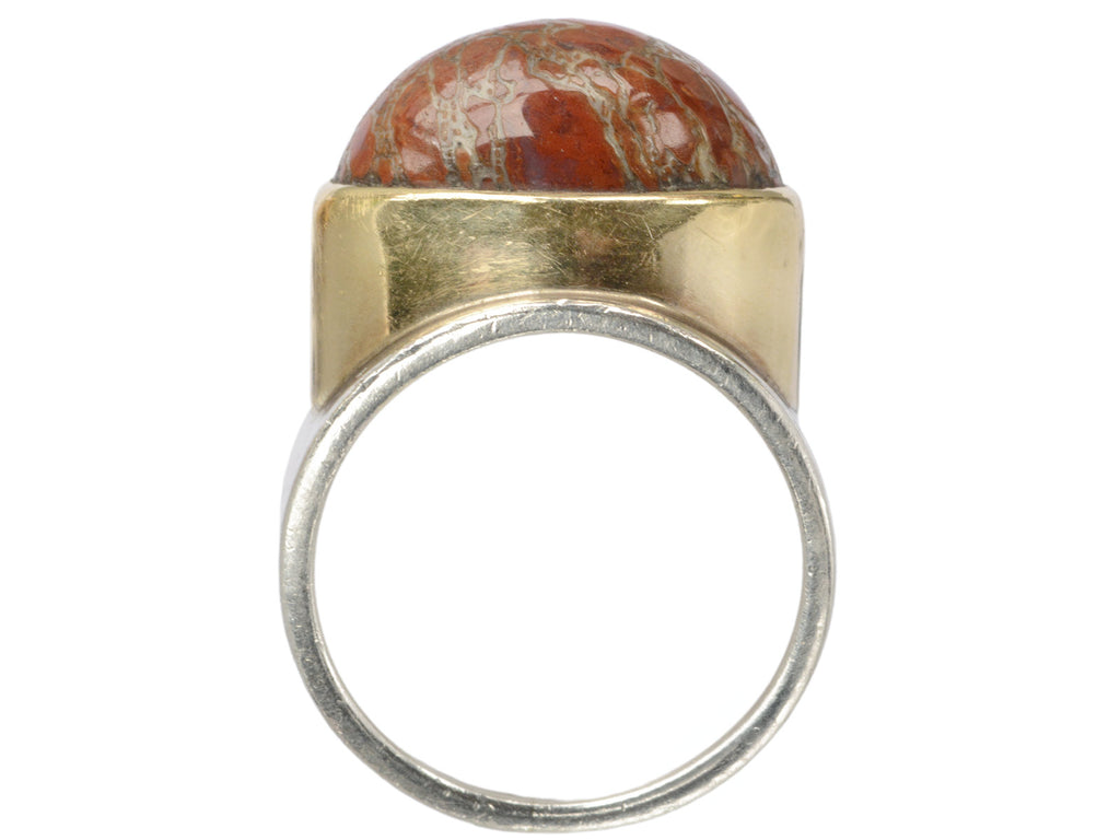 Side profile view of fossilized red jasper cabochon set in gold bezel on silver shank, shown on white background.