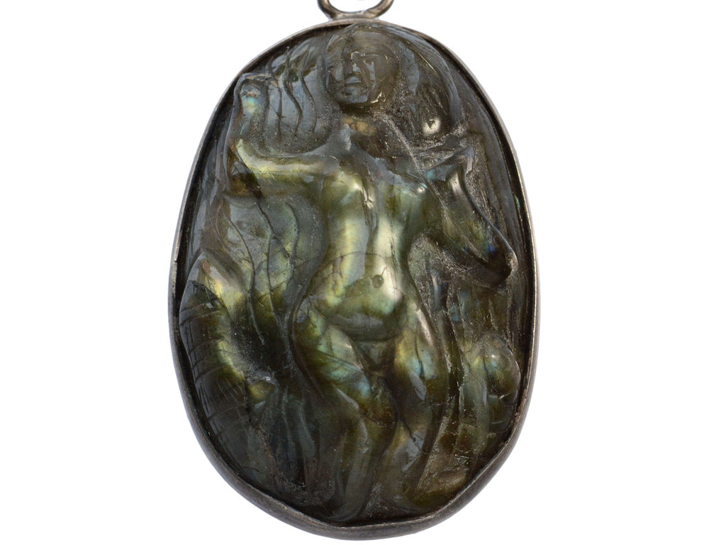 Detail of a vintage pendant necklace with labradorite carved with the image of a nude woman, on a white background.