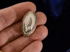 thumbnail of c1800 Georgian Sepia Miniature of an ivy leaf with the words "je ne change qu'en mourant" (shown on hand for scale)