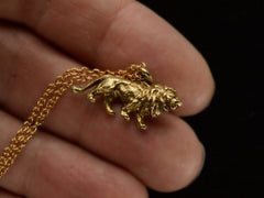 thumbnail of A detailed antique gold lion charm, hanging on cable chain. Shown on hand