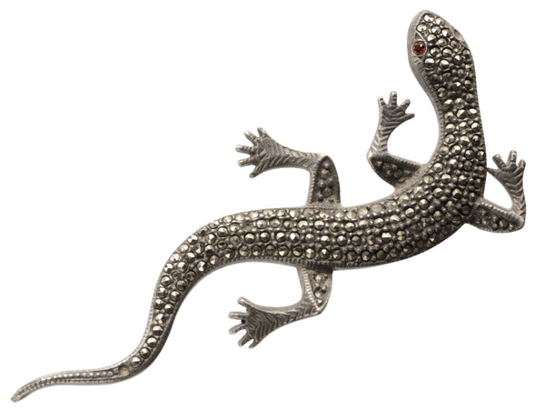 Vintage marcasite and silver lizard brooch with red eyes, on white background.