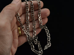 thumbnail of Hand holding a silver mariner link chain against a black background