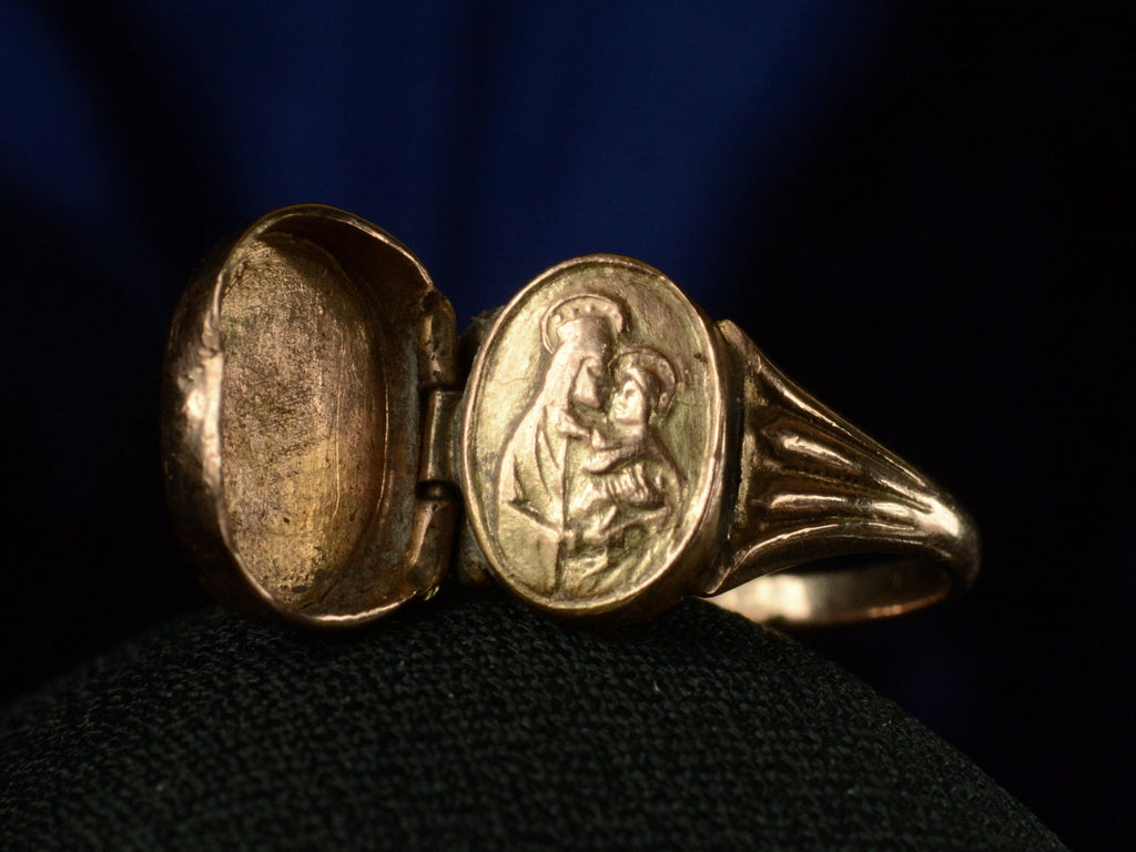 A c1920 antique signet ring shown with the locket open revealing an image of the Madonna and Child. In gold on dark background.
