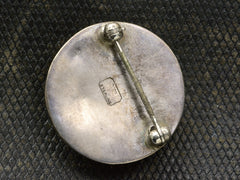 thumbnail of Reverse side of silver brooch showing pin fittings and a stamp with the letters "VS" and "STERLING"